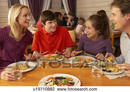 Stock Image - Family Eating Lunch Together In Restaurant. Fotosearch