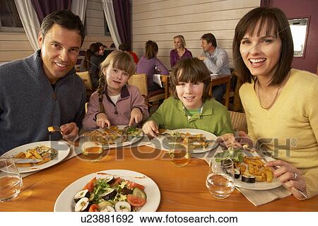 Stock Image - Family Eating Lunch Together In Restaurant. Fotosearch
