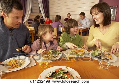Stock Photo - Family Eating Lunch Together In Restaurant. Fotosearch