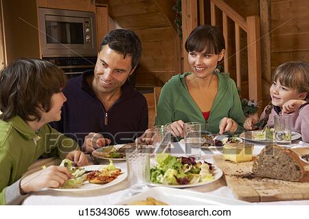 Stock Photography - Family Enjoying Meal In Alpine Chalet Together. Fotosearch