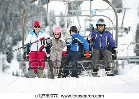 Stock Image - Family Getting Off chair Lift On Ski Holiday In Mountains. Fotosearch
