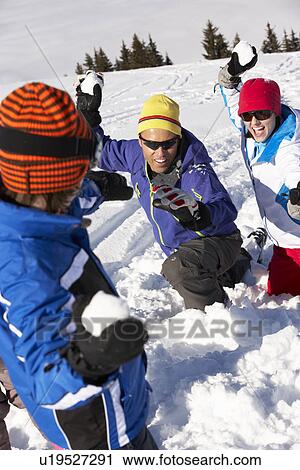 Stock Image - Family Having Snowball Fight On Ski Holiday In Mountains. Fotosearch