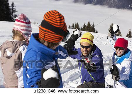 Stock Photograph - Family Having Snowball Fight On Ski Holiday In Mountains. Fotosearch