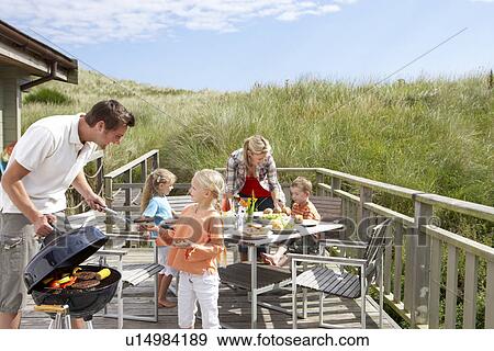 Stock Photo - Family on vacation having barbecue. Fotosearch