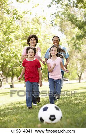 Stock Image - Family playing football in park. Fotosearch