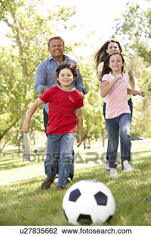 Stock Image - Family playing football in park. Fotosearch