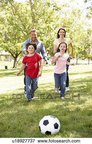 Stock Photo - Family playing football in park. Fotosearch