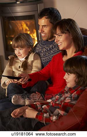 Picture - Family Relaxing Watching TV By Cosy Log Fire. Fotosearch