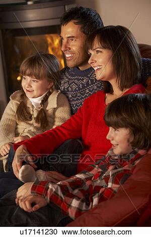 Family Relaxing Watching TV By Cosy Log Fire View Large Photo Image Stock Image - Family Relaxing Watching TV By Cosy Log Fire. Fotosearch