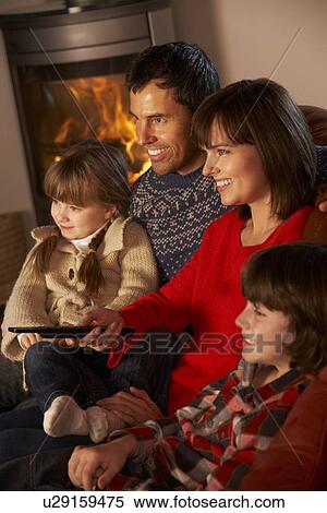 Stock Photography - Family Relaxing Watching TV By Cosy Log Fire. Fotosearch