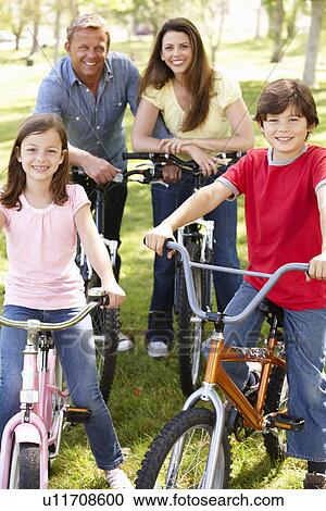 Family riding bikes in park View Large Photo Image Stock Image - Family riding bikes in park. Fotosearch