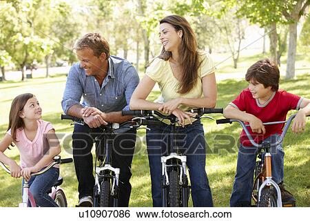 Stock Photograph - Family riding bikes in park. Fotosearch