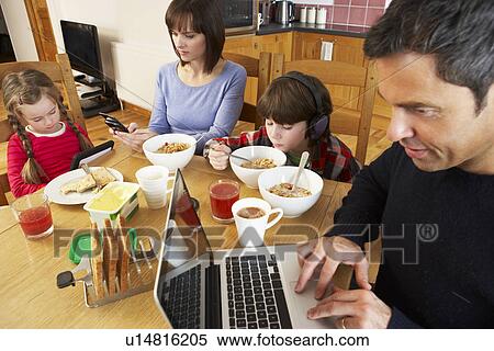 Family Using Gadgets Whilst Eating Breakfast Together In Kitchen View Large Photo Image Stock Photography - Family Using Gadgets Whilst Eating Breakfast Together In Kitchen. Fotosearch