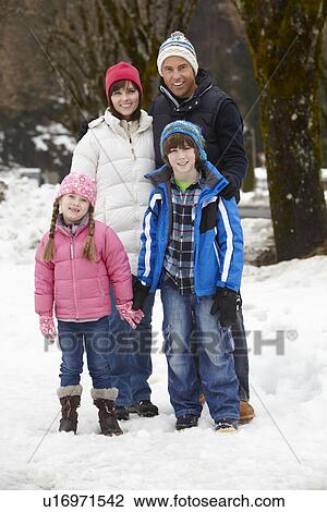 Stock Image - Family Walking Along Snowy Street In Ski Resort. Fotosearch