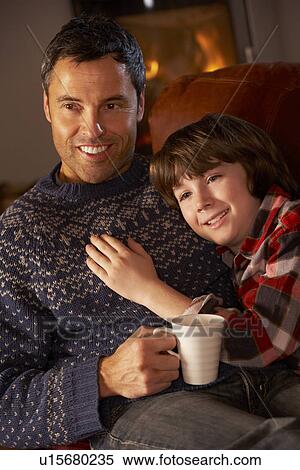 Father And Son Relaxing With Hot Drink Watching TV By Cosy Log Fire View Large Photo Image Stock Photography - Father And Son Relaxing With Hot Drink Watching TV By Cosy Log Fire. Fotosearch