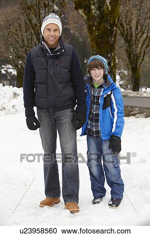 Stock Image - Father And Son Walking Along Snowy Street In Ski Resort. Fotosearch