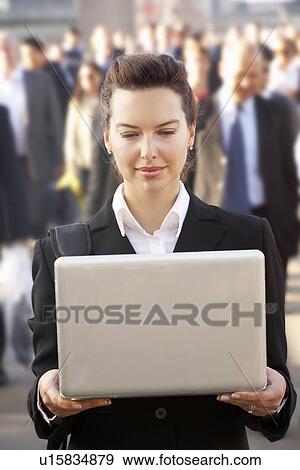 Stock Photo - Female commuter in crowd using laptop. Fotosearch