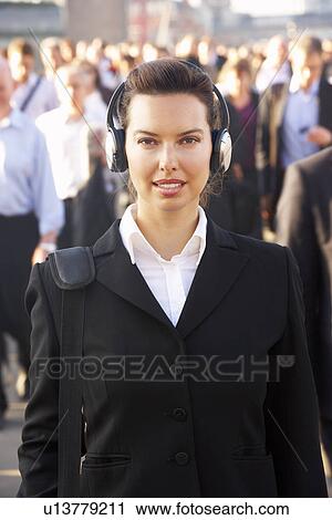 Stock Image - Female commuter in crowd wearing headphones. Fotosearch