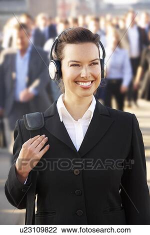 Stock Image - Female commuter in crowd wearing headphones. Fotosearch