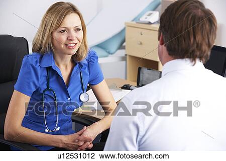 Stock Image - Female UK doctor talking to male patient. Fotosearch