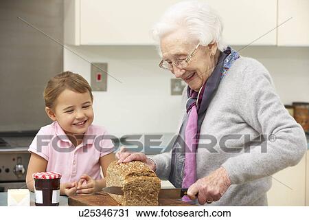 Stock Image - Grandmother and granddaughter preparing food in kitchen. Fotosearch