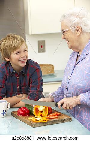 Stock Image - Grandmother and grandson preparing food in kitchen. Fotosearch