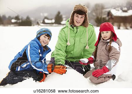 Stock Photo - Group Of Children Building Snowman Wearing Woolly Hats. Fotosearch