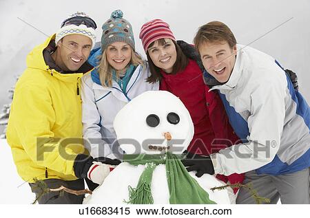 Stock Photography - Group Of Friends Building Snowman On Ski Holiday In Mountains. Fotosearch