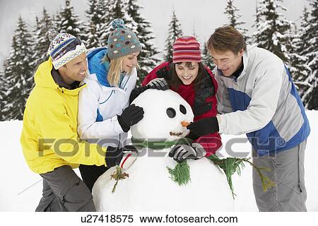 Stock Photography - Group Of Friends Building Snowman On Ski Holiday In Mountains. Fotosearch