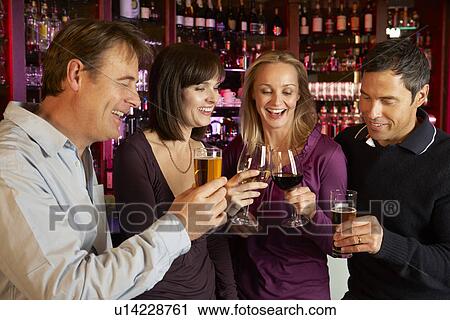 Stock Image - Group Of Friends Enjoying Drink Together In Bar. Fotosearch