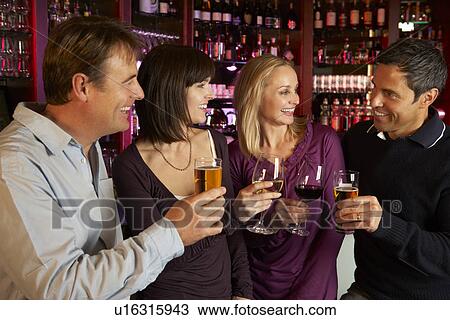 Stock Image - Group Of Friends Enjoying Drink Together In Bar. Fotosearch