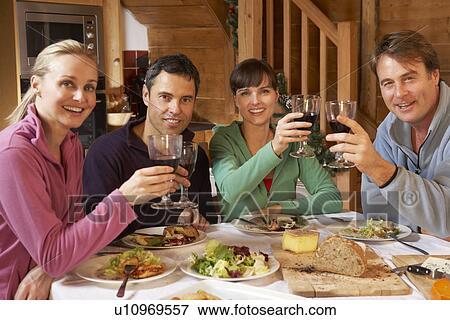 Stock Photo - Group Of Friends Enjoying Meal In Alpine Chalet Together. Fotosearch