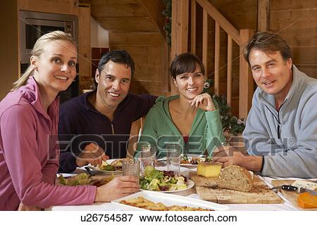 Stock Photo - Group Of Friends Enjoying Meal In Alpine Chalet Together. Fotosearch