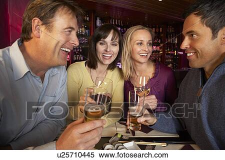 Stock Photography - Group Of Friends Enjoying Sushi In Restaurant. Fotosearch