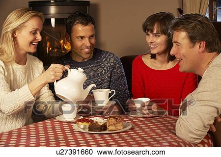 Stock Image - Group Of Middle Aged Couples Enjoying Tea And Cake Together. Fotosearch