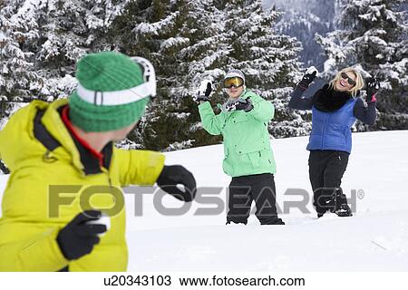 Stock Image - Group Of Young Friends Having Snowball Fight On Ski Holiday In Mountains. Fotosearch