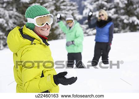 Stock Image - Group Of Young Friends Having Snowball Fight On Ski Holiday In Mountains. Fotosearch