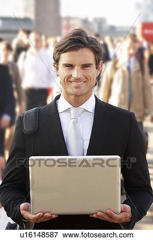 Stock Photo - Male commuter in crowd using laptop. Fotosearch