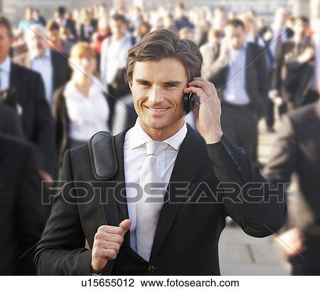 Stock Image - Male commuter in crowd using phone. Fotosearch