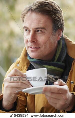 Picture - Man In Outdoor CafÃ© With Hot Drink Wearing Winter Clothes. Fotosearch