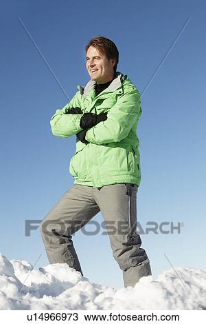 Stock Image - Man Standing In Snow Wearing Warm Clothes On Ski Holiday In Mountains. Fotosearch