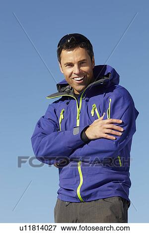 Stock Photo - Man Standing In Snow Wearing Warm Clothes On Ski Holiday In Mountains. Fotosearch