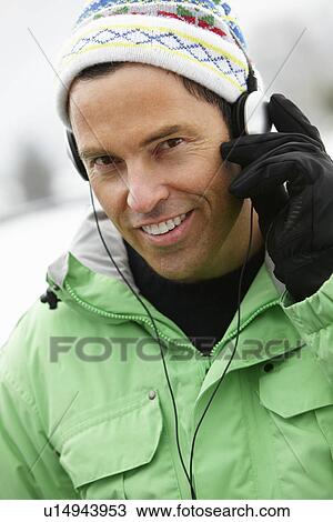 Stock Image - Man Wearing Headphones And Listening To Music Wearing Winter Clothes In Snowy Landscape. Fotosearch