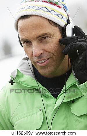 Stock Photo - Man Wearing Headphones And Listening To Music Wearing Winter Clothes In Snowy Landscape. Fotosearch