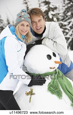 Middle Aged Couple Building Snowman On Ski Holiday In Mountains View Large Photo Image Stock Image - Middle Aged Couple Building Snowman On Ski Holiday In Mountains. Fotosearch