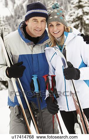Stock Photo - Middle Aged Couple On Ski Holiday In Mountains. Fotosearch