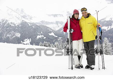 Stock Photo - Middle Aged Couple On Ski Holiday In Mountains. Fotosearch