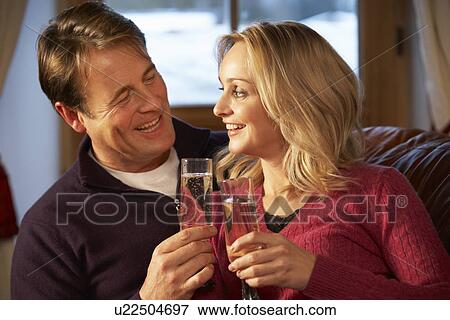 Stock Photo - Middle Aged Couple Sitting On Sofa With Glasses Of Champagne. Fotosearch