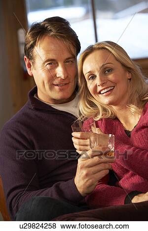 Stock Photo - Middle Aged Couple Sitting On Sofa With Glasses Of Whisky. Fotosearch