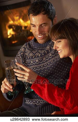 Middle Aged Couple Sitting Sofa By Cosy Log Fire With Glass Of Champagne View Large Photo Image Stock Image - Middle Aged Couple Sitting Sofa By Cosy Log Fire With Glass Of Champagne. Fotosearch